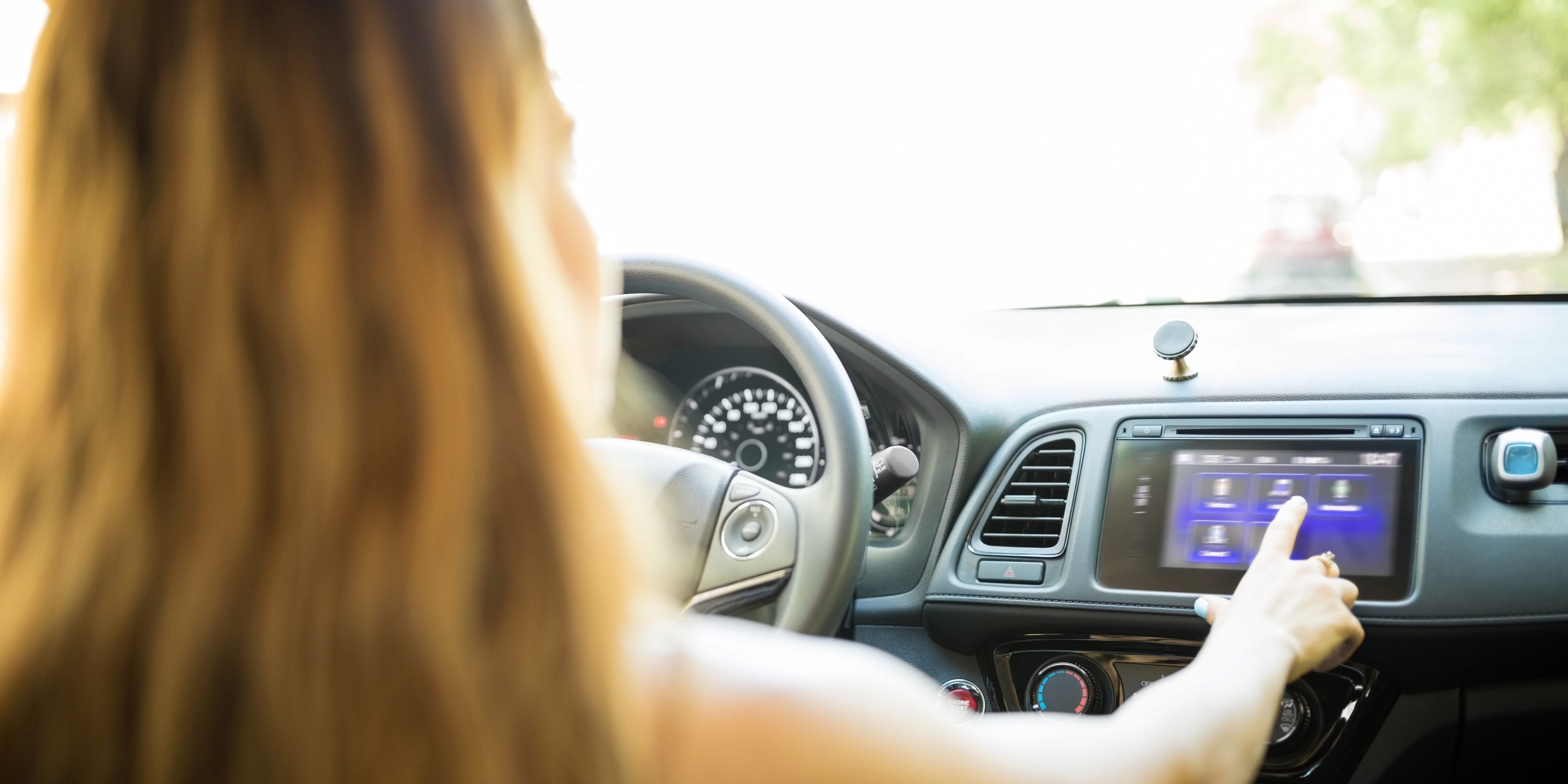woman driving a car while distracted pushing buttons